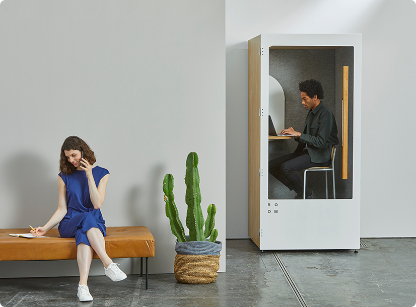 Modern office scene with a woman on a bench and a man working in a soundproof booth.